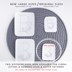 Two white stick and stitch embroidery patterns, a floral letter 'B' and number '3', in original 2" and new 3.5" sizes, on a gray mat.