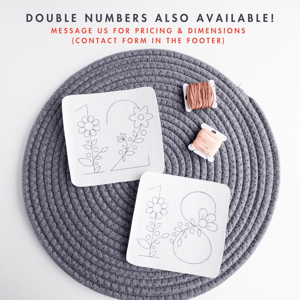 Two white stick and stitch floral number patterns, "10" and "18", on a gray mat with peach embroidery floss.
