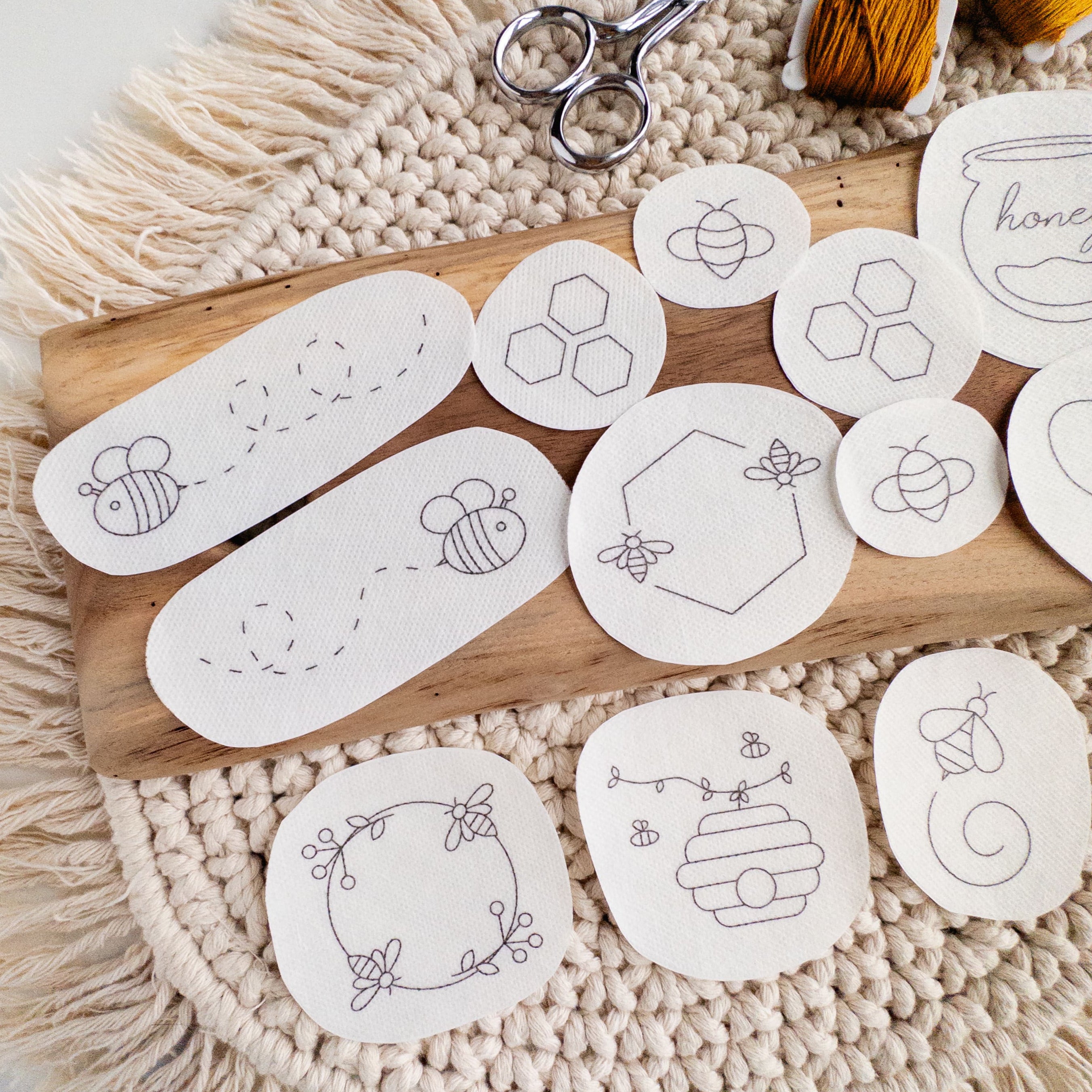 White water-soluble stick and stitch patches with various black honeybee and honeycomb embroidery designs.