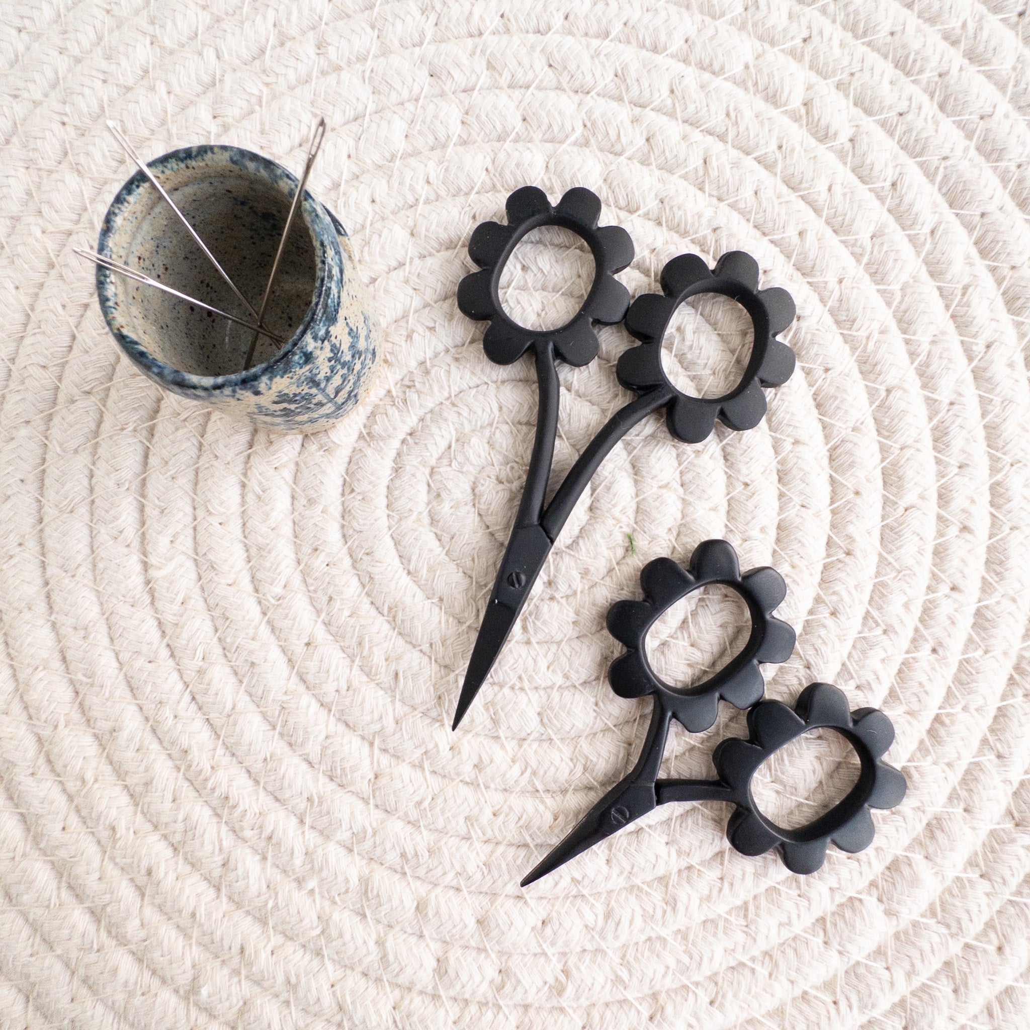 Black floral-handled scissors on a textured white surface