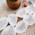 White water-soluble stick and stitch butterfly embroidery patterns on a wooden board with yarn and a basket.