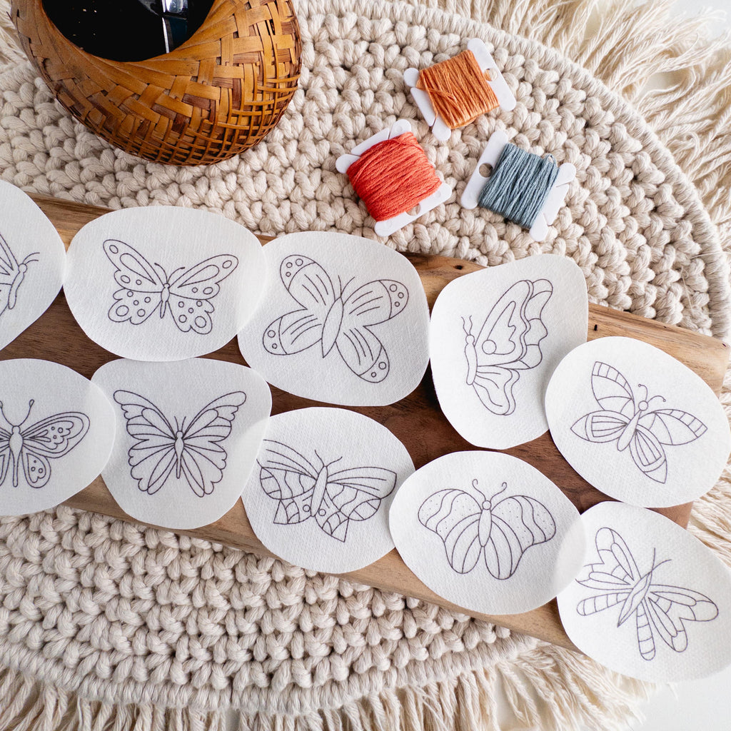 12 butterfly stick and stitch embroidery patterns on water-soluble paper, with orange and blue floss.