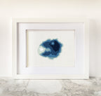 Framed Crater Lake cross-stitch art with a minimalist blue bathymetric map design on white fabric.