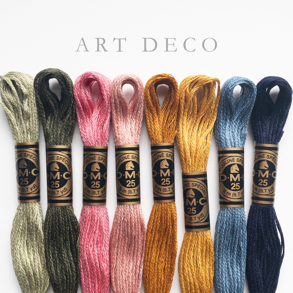 Eight spools of DMC Art Deco embroidery floss in green, pink, gold, and blue shades.
