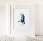 Framed Flathead Lake cross-stitch art with minimalist blue and green bathymetric map design.