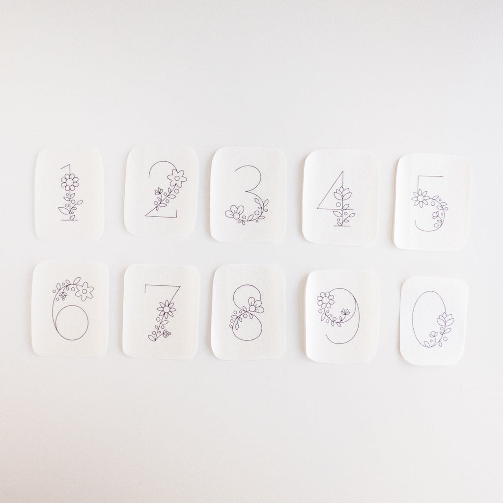Ten white stick and stitch embroidery patterns, each with a floral-decorated number from 0 to 9.