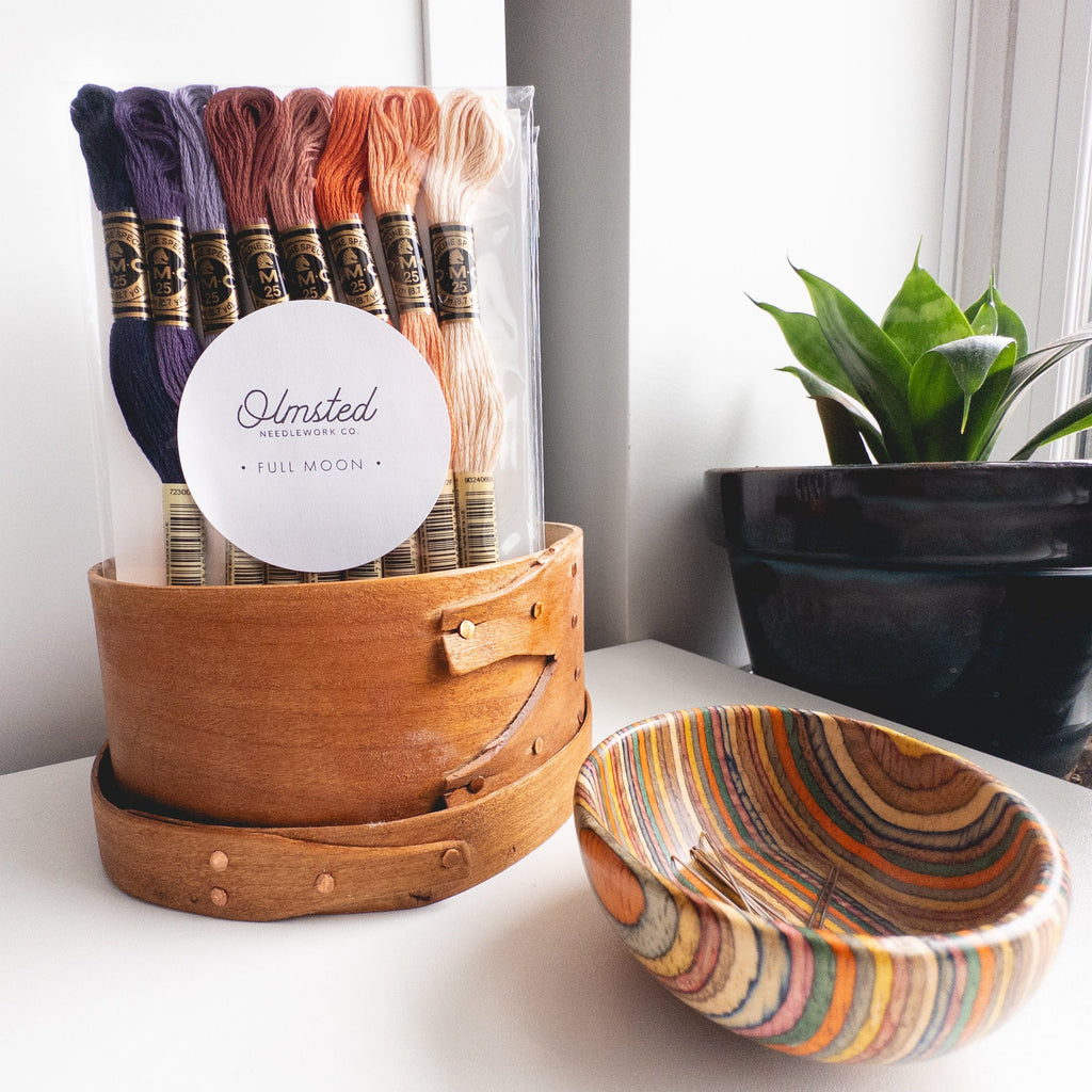 DMC "Full Moon" embroidery floss bundle with 8 skeins in a wooden box, beside a colorful wooden bowl.