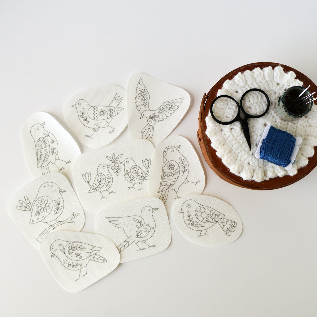 Nine folk bird stick and stitch embroidery patterns on white washaway stabilizer, with a sewing kit.