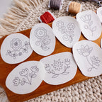 Scandinavian folk flower embroidery patterns on water-soluble stabilizer stickers, with floss and scissors.