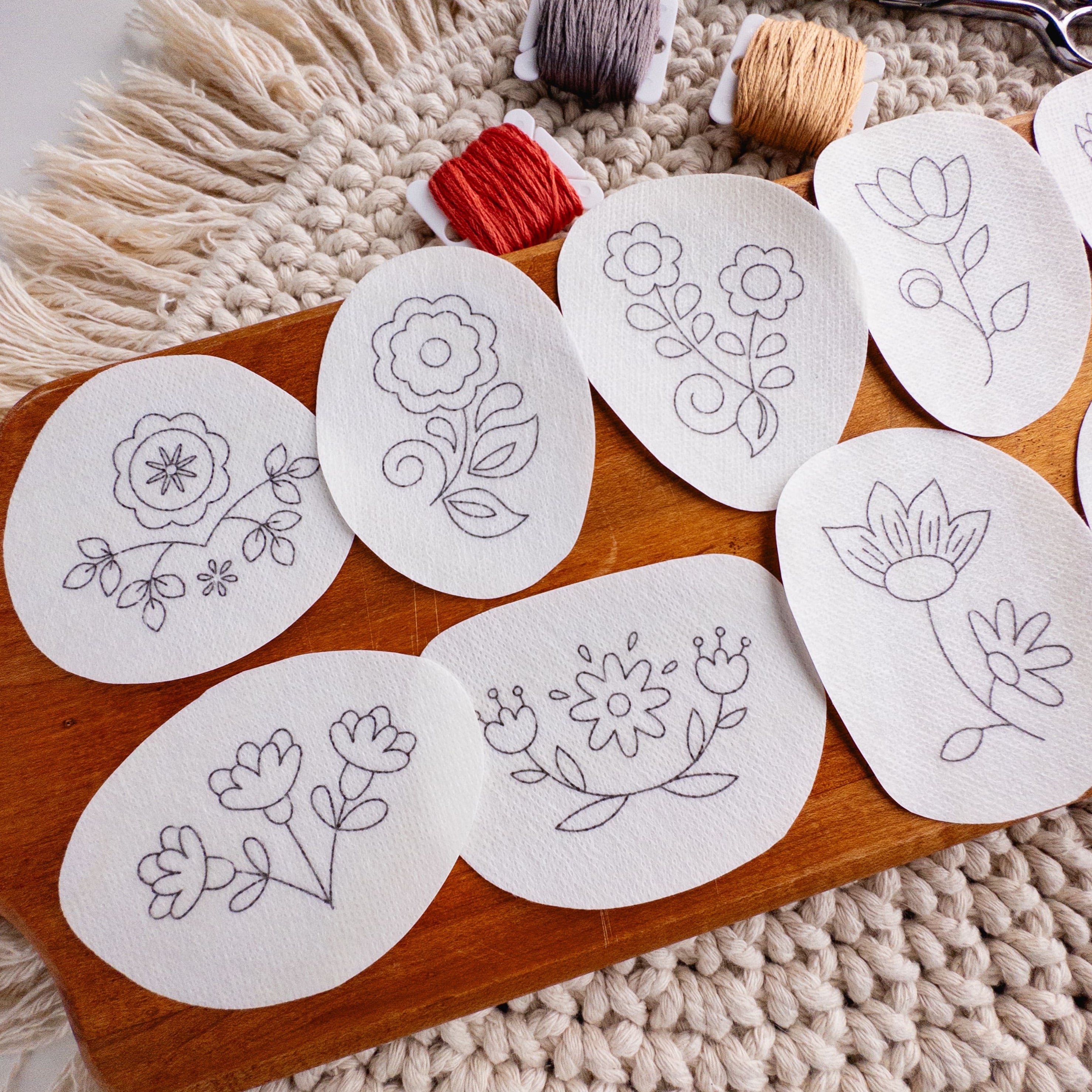 Scandinavian folk flower embroidery patterns on water-soluble stabilizer stickers, with floss and scissors.