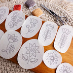 Scandinavian folk flower stick and stitch embroidery patterns on a wooden board with floss and scissors.