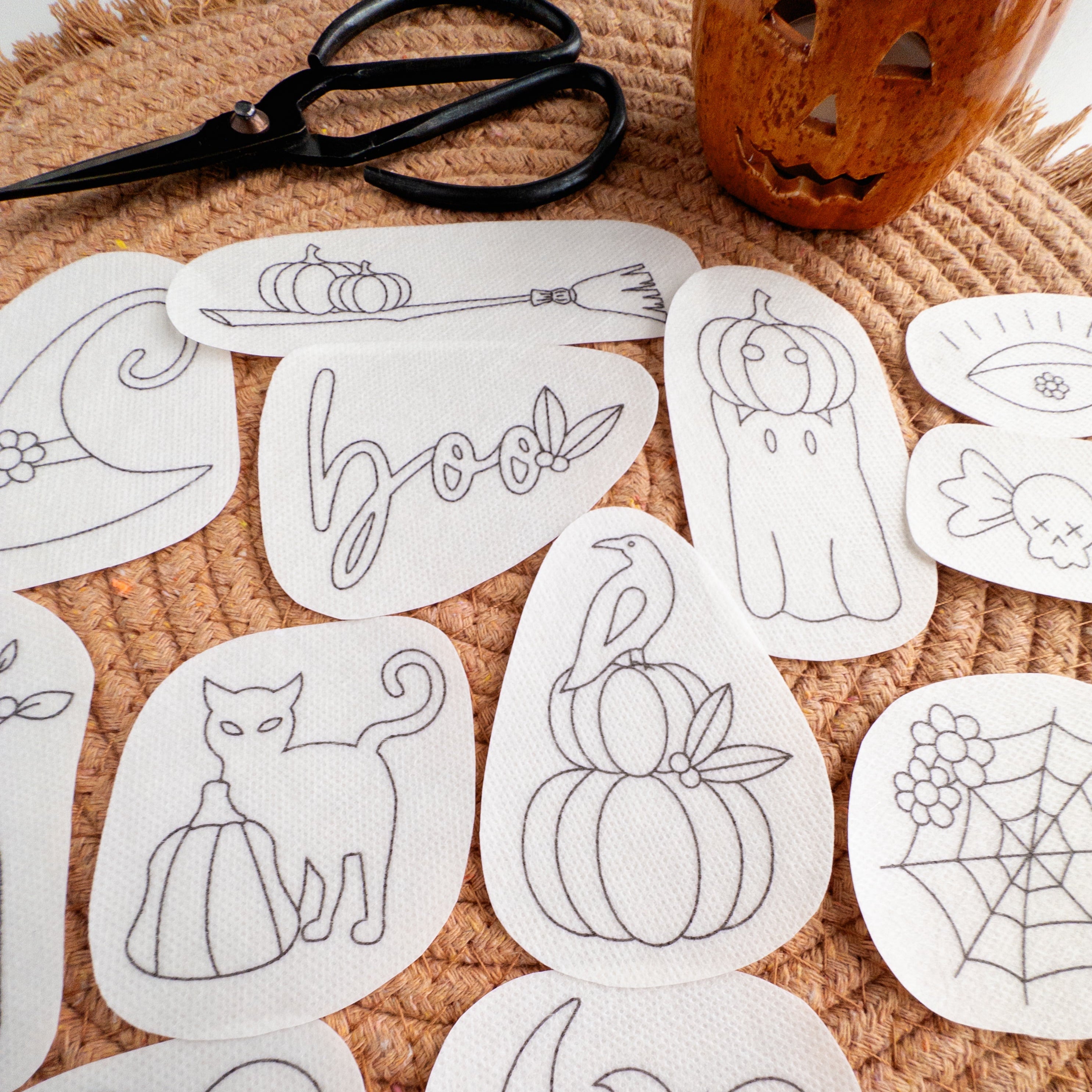 White water-soluble embroidery patches with 12 Halloween designs like pumpkins, ghosts, and a witch hat.
