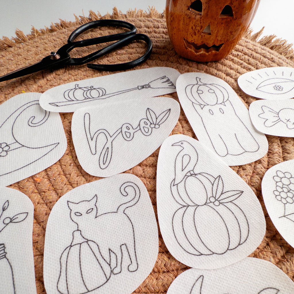 Halloween stick and stitch embroidery patterns: ghost, cat, pumpkin, witch hat, and "boo" designs on white stabilizer.