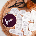 Halloween stick and stitch embroidery patterns: 12 spooky designs on white patches, with a "boo" hoop.