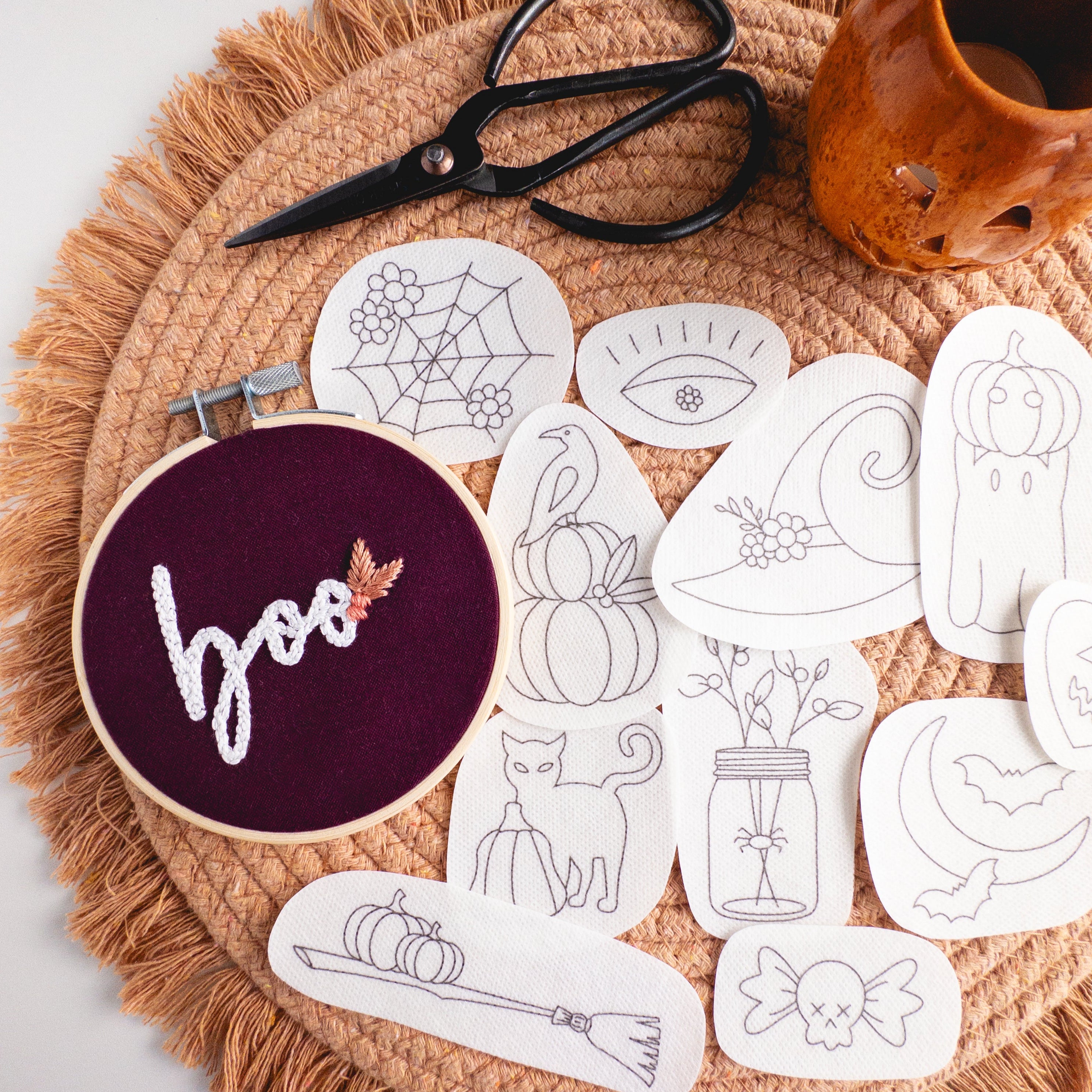 Halloween stick and stitch embroidery patterns: 12 spooky designs on white patches, with a "boo" hoop.