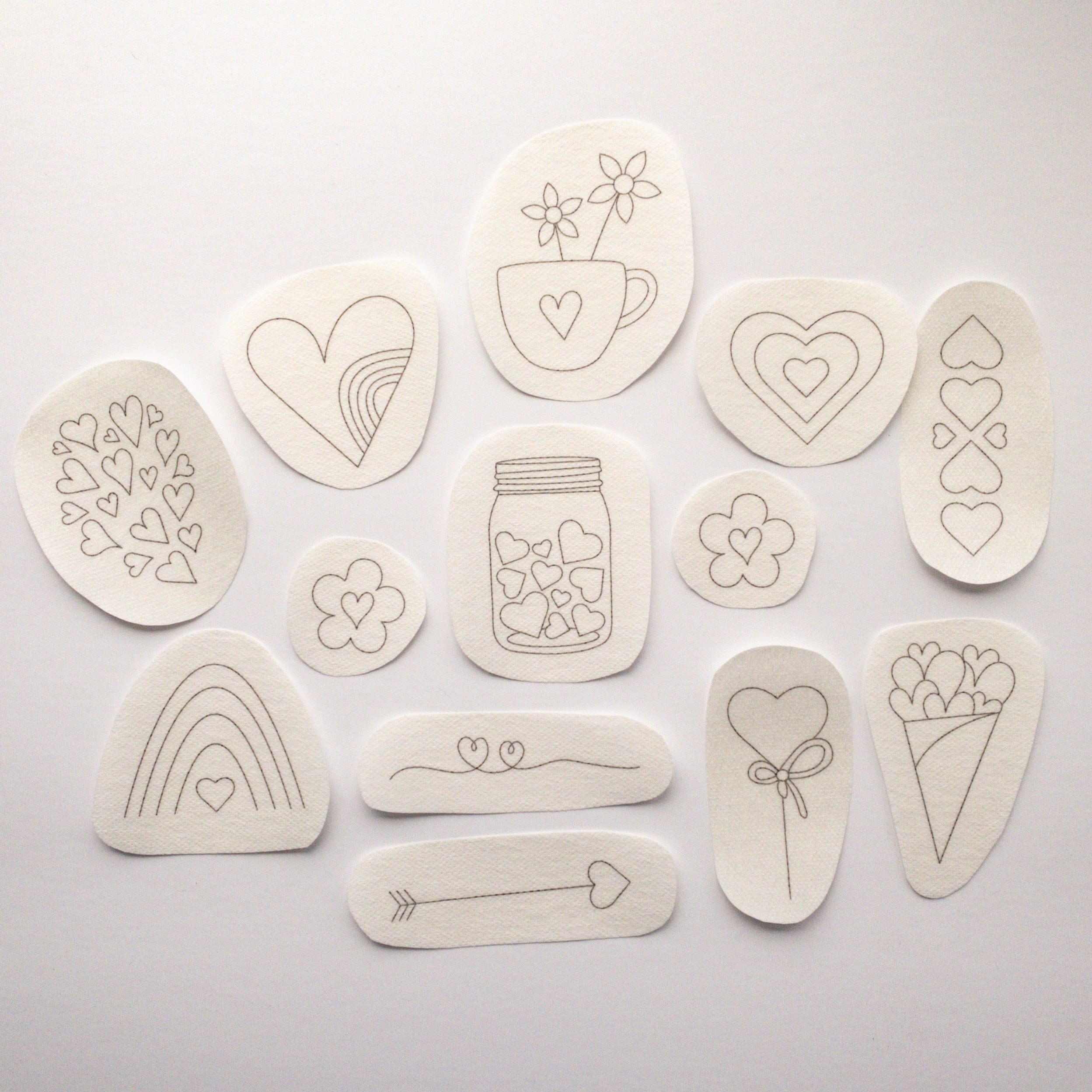 13 beige water-soluble heart embroidery stick and stitch patterns, ranging from 1.1" to 3" in diameter.