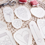 White water-soluble heart embroidery stick and stitch patterns on a crocheted surface with floss and scissors.