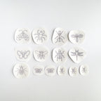 14 black outline insect embroidery patterns on white water-soluble stabilizer patches, assorted bug designs and sizes.