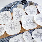 Assorted insect stick and stitch embroidery patterns on white water-soluble stabilizer, with scissors and floss.