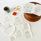 Washaway stabilizer sheets with ten black-outlined Jack O'Lantern embroidery patterns, scissors, and orange floss.