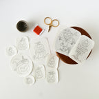Ten white washaway embroidery patterns featuring various Jack O'Lanterns, a scarecrow, and a sign, with thread and scissors.