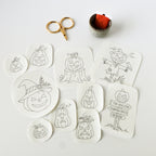 Ten Jack O'Lantern stick and stitch embroidery patterns on white washaway stabilizer, with gold scissors and orange floss.