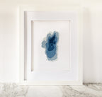 Framed Lake Tahoe cross-stitch art with blue bathymetric map design on white fabric.