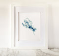 Framed Lake Winnipesaukee cross-stitch art with minimalist blue bathymetric map on white fabric.
