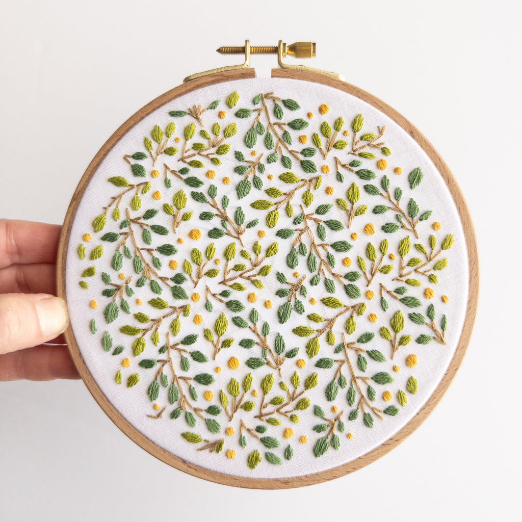 Embroidered lemon grove botanical design in a 6-inch wooden hoop, featuring green leaves and yellow berries.