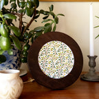 Round dark wood frame with a white embroidered lemon grove pattern of green leaves and yellow dots.
