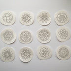Twelve round, white water-soluble stick and stitch mandala embroidery patterns with gray outlines.