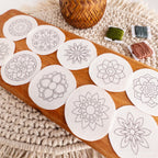 Twelve round, white mandala stick and stitch embroidery patterns on a wooden board with floss.