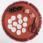 12 mini autumn botanical stick and stitch embroidery patterns on white water-soluble stabilizer, with thread and scissors on a terracotta mat.