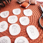 Twelve mini mushroom stick and stitch embroidery patterns on white water-soluble patches, with orange thread.