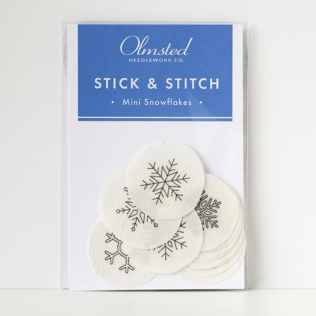 Pack of 12 white, round, water-soluble Stick & Stitch mini snowflake embroidery patterns, 1" diameter.