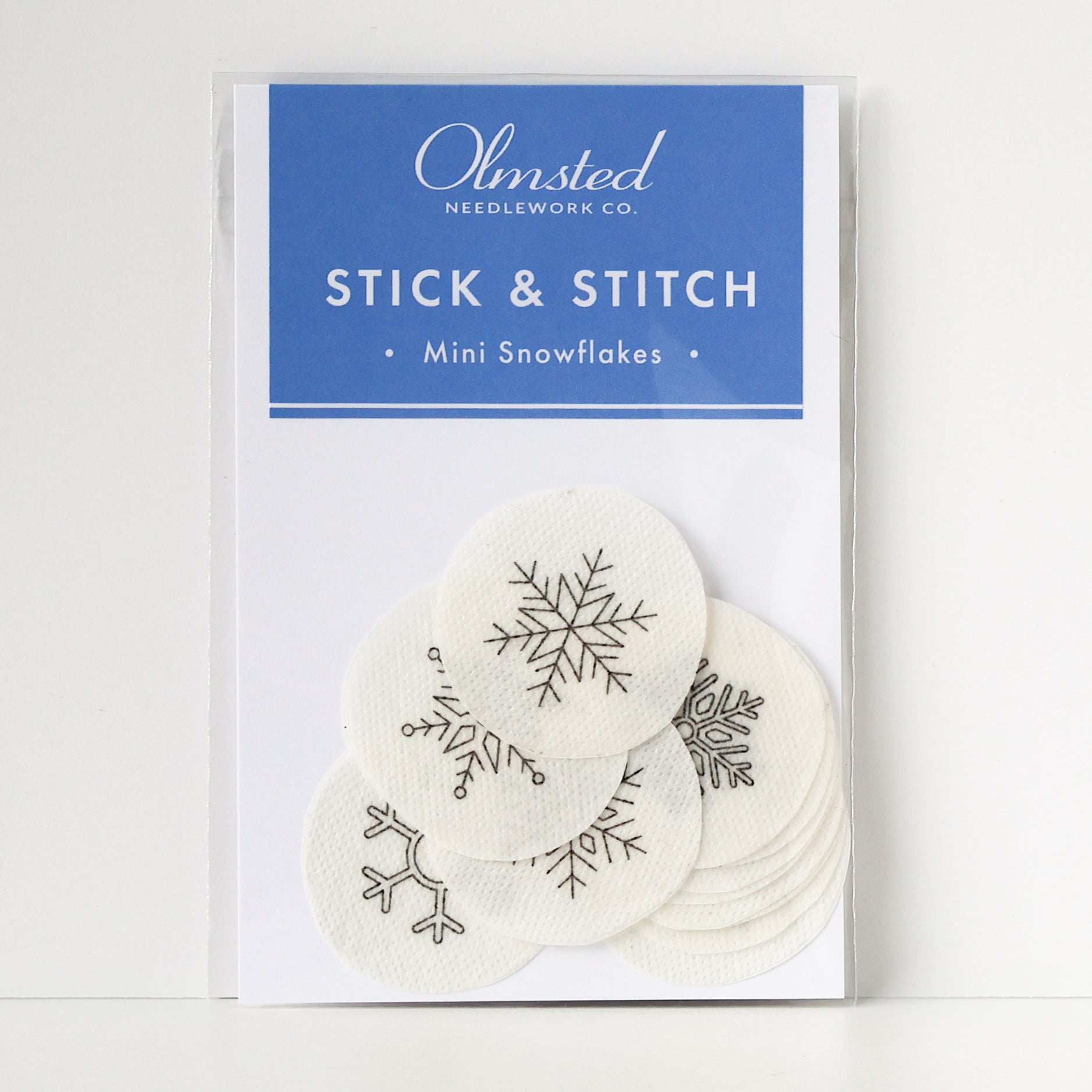 Pack of 12 white, round, water-soluble Stick & Stitch mini snowflake embroidery patterns, 1" diameter.