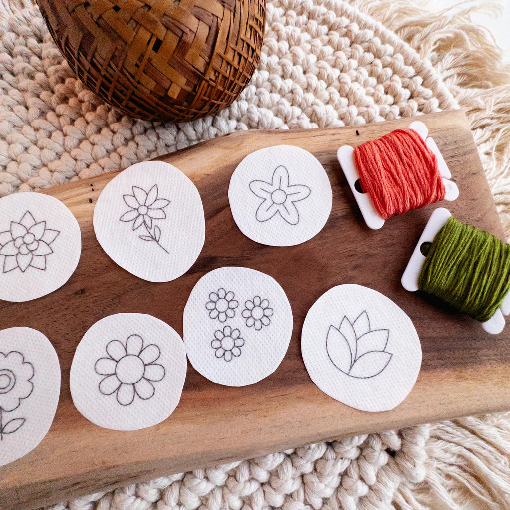 Mini flower stick and stitch embroidery patterns on water-soluble stabilizer, with orange and green floss.