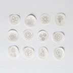 Twelve white water-soluble stick and stitch mini flower embroidery patterns with black outlines.