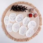 Nine mushroom stick and stitch embroidery patterns on white water-soluble stabilizer patches, with thread and pinecone.