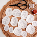 13 pumpkin stick and stitch embroidery patterns on water-soluble stabilizer, with scissors and floss.