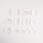 Thirteen white water-soluble stabilizer patches with various gray pumpkin embroidery patterns.