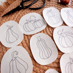 White water-soluble stabilizer patches with black outline pumpkin embroidery patterns on a woven mat.