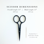 Matte black 3.5" embroidery scissors with 1.5" stainless steel blades next to a needle for size reference.