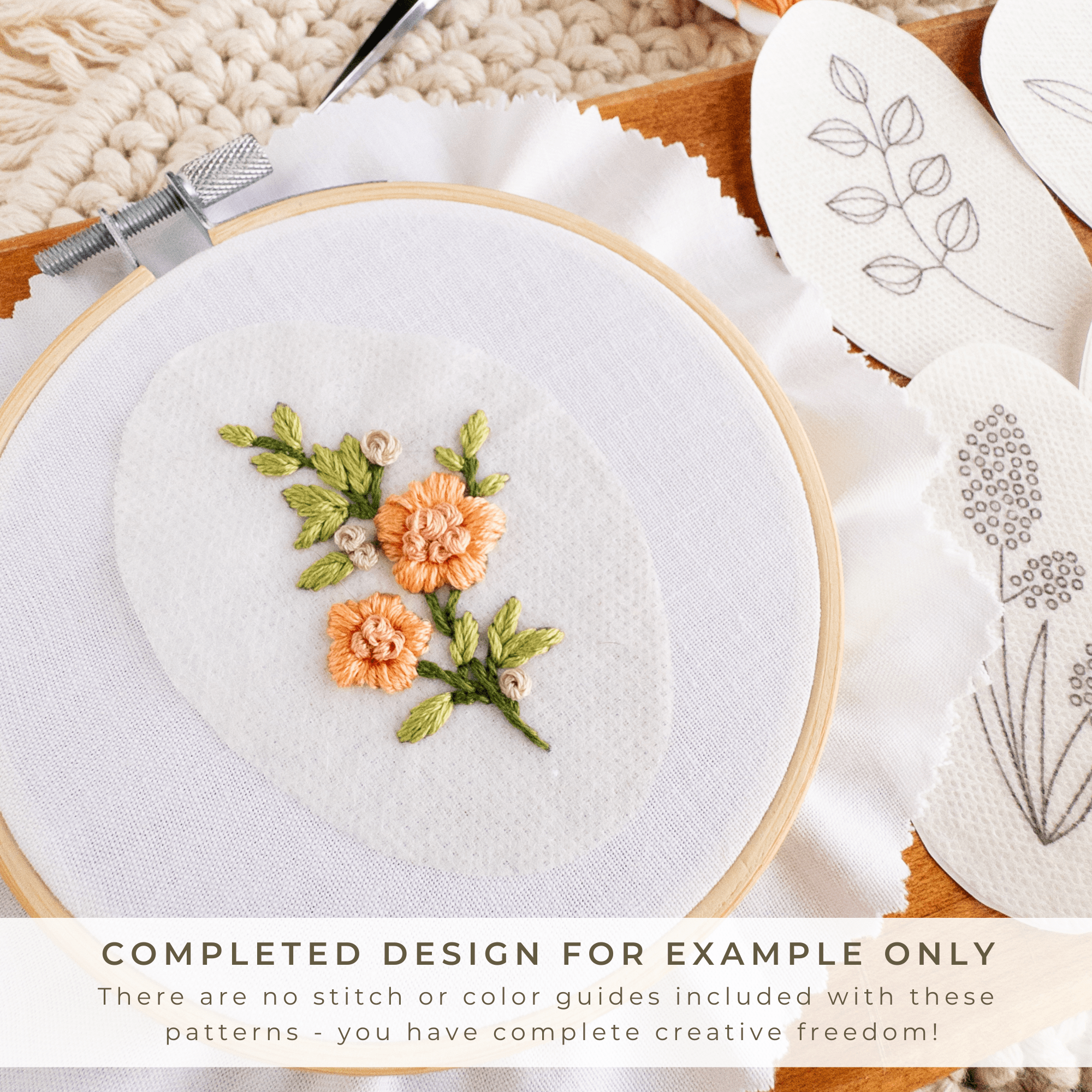 Embroidery hoop with a stitched orange wildflower design and water-soluble stick and stitch patterns.