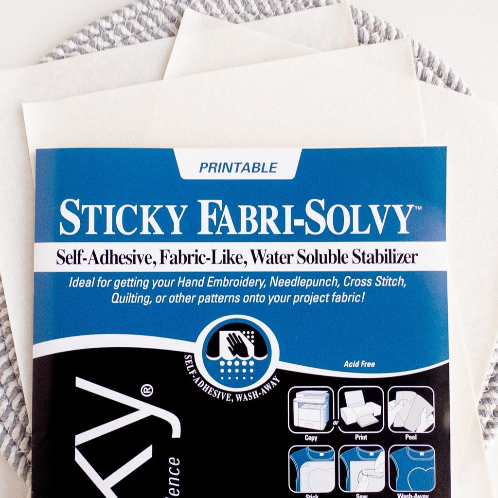 Sulky Sticky Fabri-Solvy printable embroidery transfer paper with instructions, on a stack of white sheets.