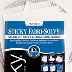 Sulky Sticky Fabri-Solvy printable embroidery transfer paper with instructions, on a stack of white sheets.