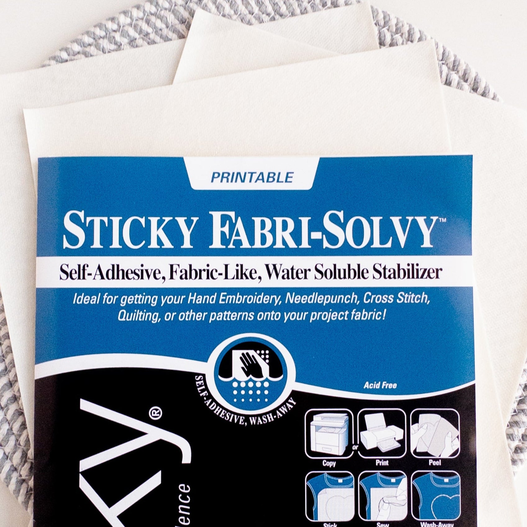Sulky Sticky Fabri-Solvy printable embroidery transfer paper with instructions, on a stack of white sheets.