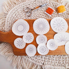 Sunburst Stick and Stitch embroidery patterns on a wooden board with scissors and orange/yellow floss.