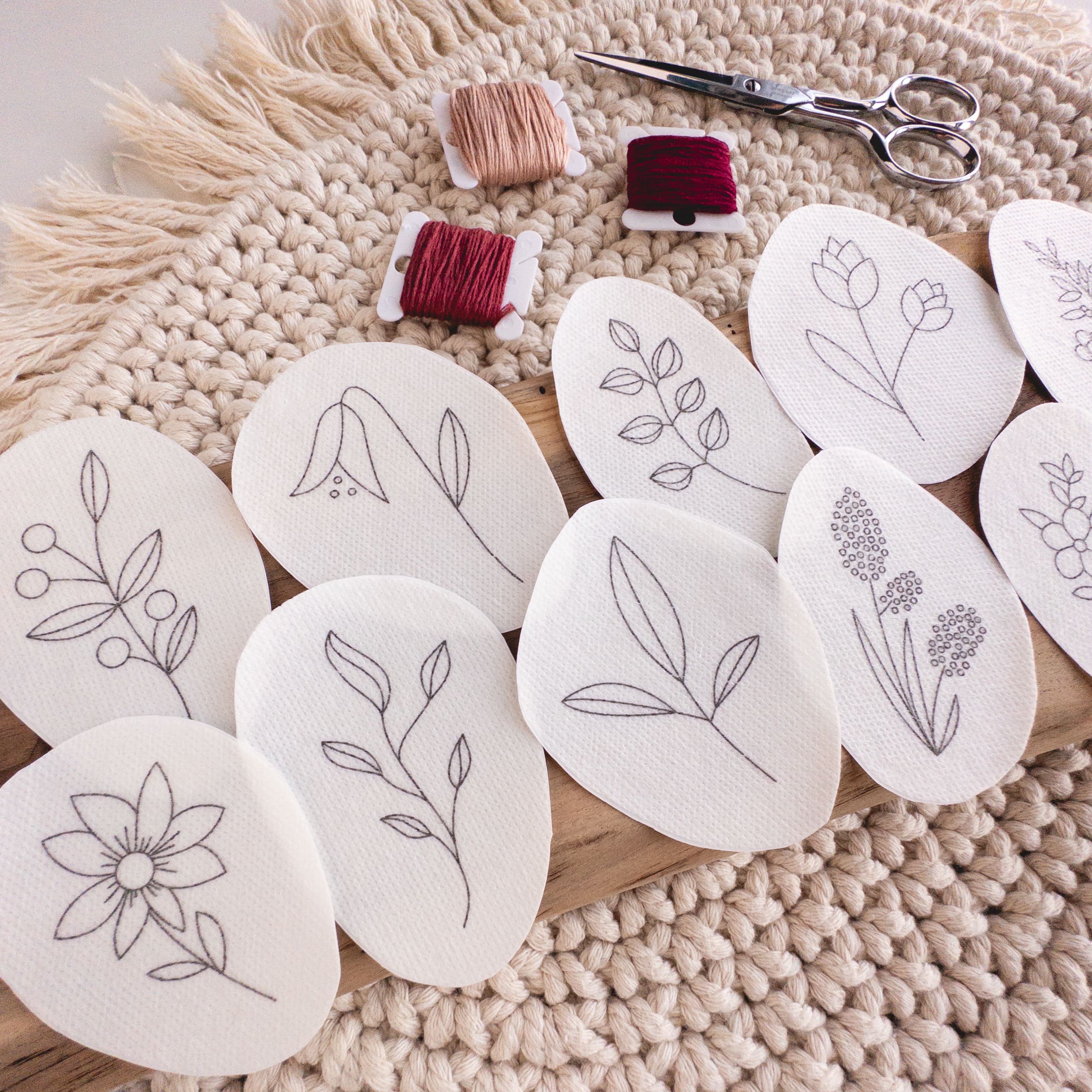 Wildflower stick and stitch embroidery patterns on water-soluble stabilizer, with floss and scissors.