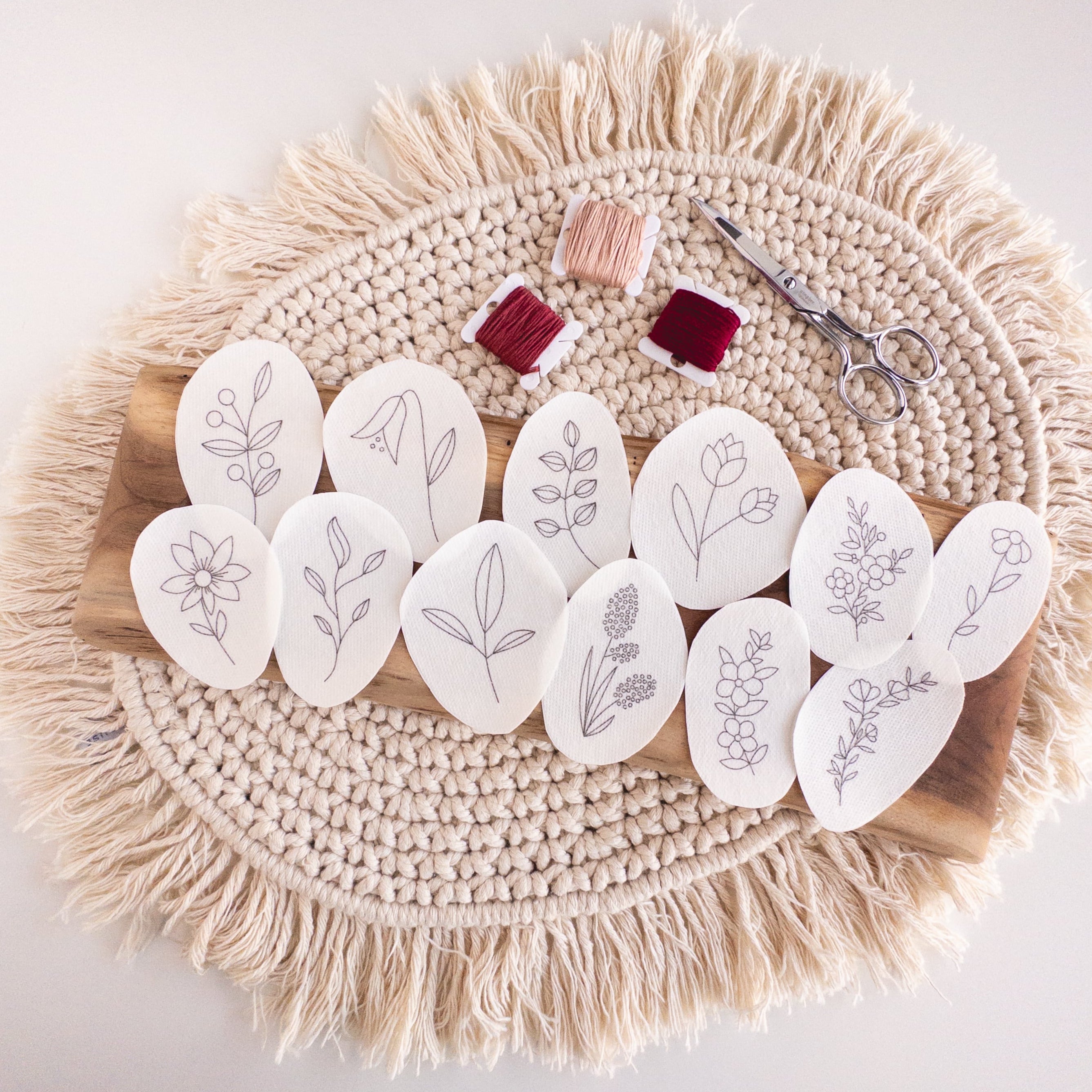 12 water-soluble wildflower stick and stitch embroidery patterns on a wood board with floss and scissors.